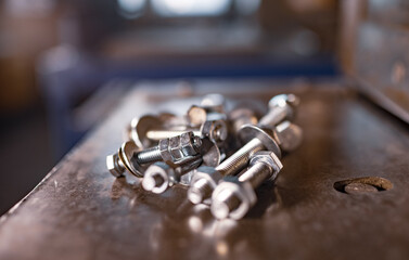 Metal chrome bolts and nuts lie on the shiny metal surface of the machine