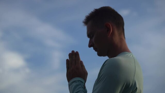 Young Man pray on blue sky background. Repentance, regret and hope concept 