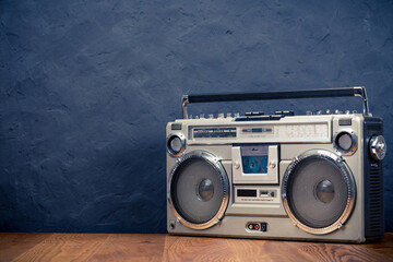 Retro boombox ghetto blaster outdated portable radio receiver with cassette recorder from 80s front concrete black wall background. Rap, Hip Hop, R&B music concept. Vintage old style filtered photo