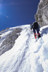 mountaineers with ice axes climb a sheer ice wall on a snowy alpine slope