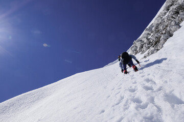 Naklejka na ściany i meble mountaineers with ice axes climb a sheer ice wall on a snowy alpine slope