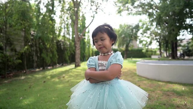 Funny little girl in princes dressed  standing at park outdoor.