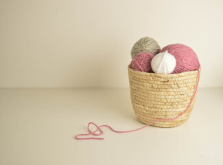 pastel colored woolen balls in basket with crochet hooks