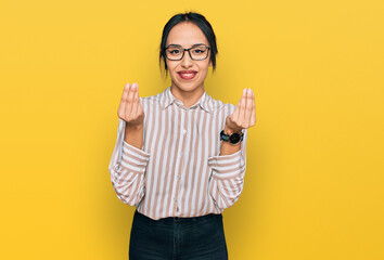 Young hispanic girl wearing casual clothes and glasses doing money gesture with hands, asking for...