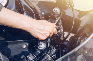 Close up of motorcycle rider hand inserting the key for starting the motorcycle engine. A...
