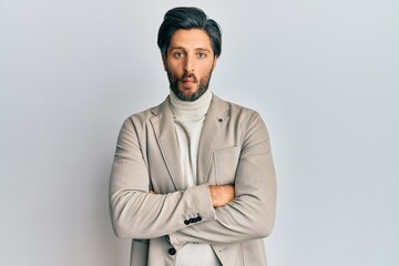Young hispanic man with arms crossed gesture making fish face with mouth and squinting eyes, crazy and comical.