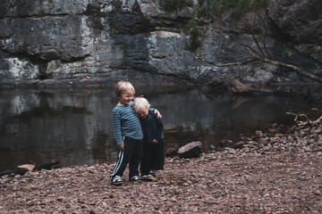 Fototapeta premium Two little boys standing together in front of rock pool on outdoor adventure