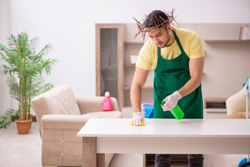 Young male contractor wearing prickly wreath on head cleaning th