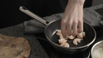 Man put shrimps on a non stick pan