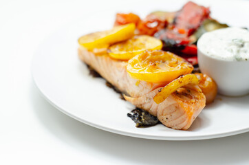 Grilled salmon fillet served with roasted vegetables with cucumber and dill sauce