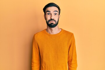 Young hispanic man wearing casual clothes puffing cheeks with funny face. mouth inflated with air,...