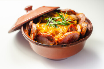 Traditional Polish dish called bigos made of sauerkraut, sausage and mushrooms, food served warm in a ceramic bowl