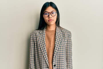 Young chinese woman wearing business style and glasses relaxed with serious expression on face....