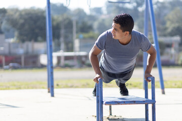 Fototapeta premium Mexican man training on a playground, poor town