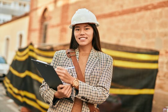 Young asian architect woman smiling happy writing on clipboard at the city.