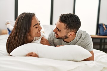 Fototapeta premium Young latin couple smiling happy hugging on the bed at home.