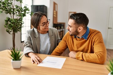 Couple smiling happy reading document at the office.