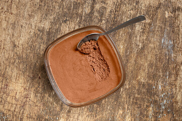 Traditional French chocolate mousse in a bowl and a spoon on the old wooden background, top view