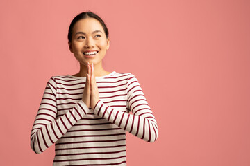 Dreamy Young Asian Female Standing With Clasped Hands And Looking Aside