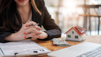 Real estate agent with house model hand putting signing contract,have a contract in place to...