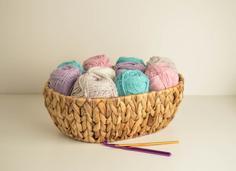 pastell coloured woolen balls in a basket  with crochet hooks for crocheting and handicraft