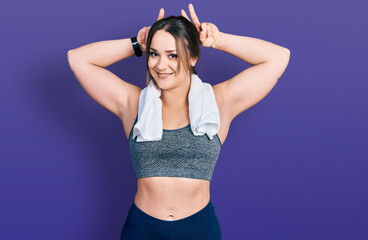 Obraz premium Young hispanic girl wearing sportswear and towel posing funny and crazy with fingers on head as bunny ears, smiling cheerful