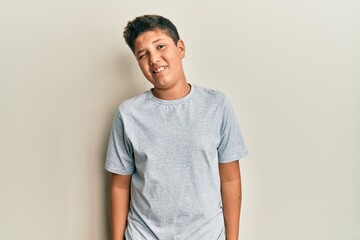 Teenager hispanic boy wearing casual grey t shirt winking looking at the camera with sexy expression, cheerful and happy face.
