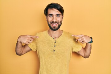 Obraz premium Young hispanic man wearing casual clothes looking confident with smile on face, pointing oneself with fingers proud and happy.