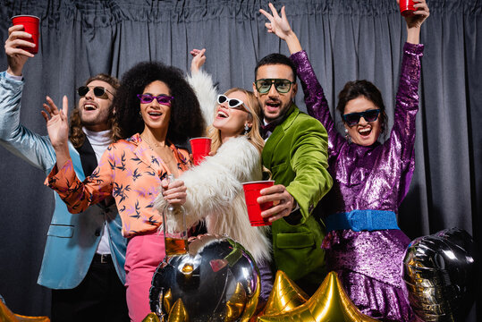 smiling interracial friends in sunglasses having party on grey background. - Powered by Adobe