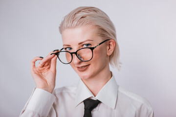 Fashionable portrait of a woman dressed in men's clothing. Girl in a white shirt and tie on a white...