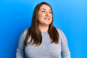 Obraz premium Beautiful brunette plus size woman wearing casual clothes looking away to side with smile on face, natural expression. laughing confident.