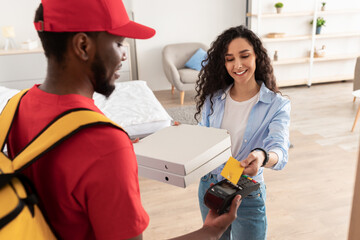 Black delivery man holding POS machine for payment