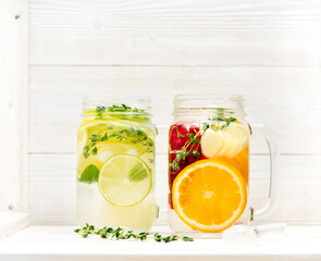 Summer cold lemonade with oranges, limes, ginger and currant berries in a glass jar on a white wooden background