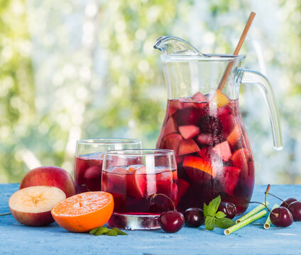 Refreshing sangria or punch with fruits in glasses and pincher