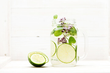 Summer infused detox.cold lemonade with lime mint in a glass jar on a white wooden background