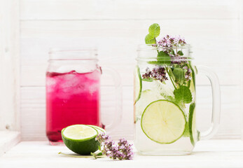 Summer infused detox cold waters with limes, cherries and berries in glass jars freemason on white wooden background
