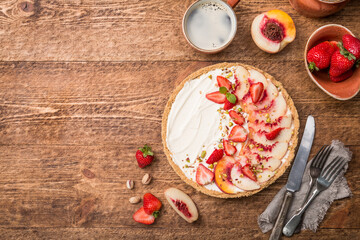 Delicious Tart with honey and mascarpone cheese cream and fresh peaches and strawberries, top view
