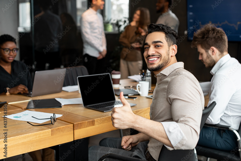 Wall mural arab businesman sitting at desk showing thumbs up gesture