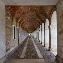 Large symmetrical exterior corridor with arches and columns in the old royal palace of Aranjuez.