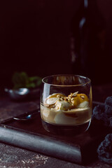 Ice cream with caramel topping and Irish cream liqueur in a glass over dark background.