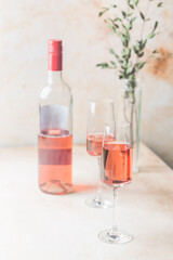 Two glasses and bottle of rose wine on light background.