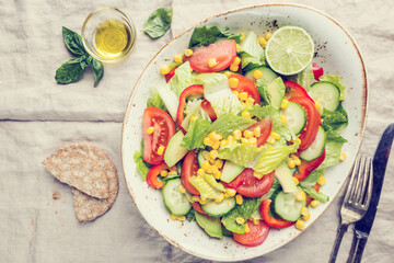 Healthy vegetable salad of fresh tomato, cucumber, lettuce and corn on plate, top view. Diet menu.
