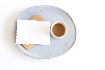 Blank paper sheet card in a bowl and a cup of coffee. Minimalist ceramics set Business template, copy space, flat lay. Free place for your text.