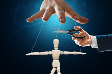 A man's hand cuts the threads between the puppeteer and the puppet with scissors. The concept of...