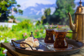 Glass Cup of turkish tea served in traditional style with summer outdore view