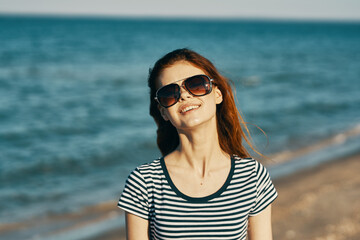 cheerful woman in a t-shirt and glasses are resting on the seashore in the mountains