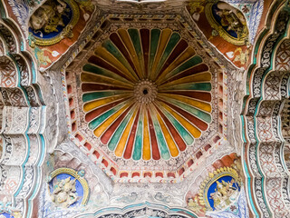 The ornate, colorfully painted ceiling of the ancient 17th century Maratha Palace in the town of...