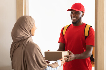 Black delivery man holding box giving it to muslim customer