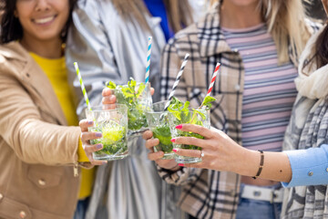 Lifestyle outdoor Friends drinking cocktails in an outdoors snack bar restaurant in the city in summer. Happy people cheering with mojito and having fun. High quality photo