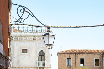 Old street lamp over a Venice street, with exposed cables.